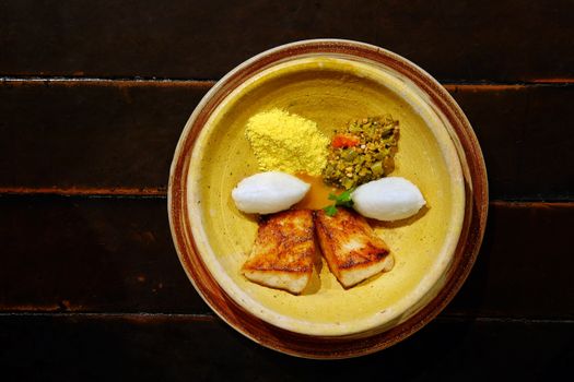 Top-down view of a gourmet fish dish with diverse sides on a rustic table.