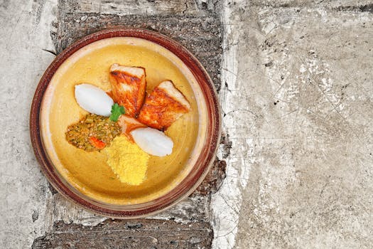 Top view of a gourmet fish meal with rice, crisps, and garnishes on a rustic plate.
