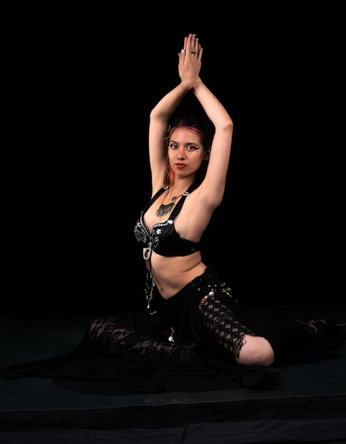 Free A woman in a belly dance pose, wearing ornate attire against a black backdrop. Stock Photo
