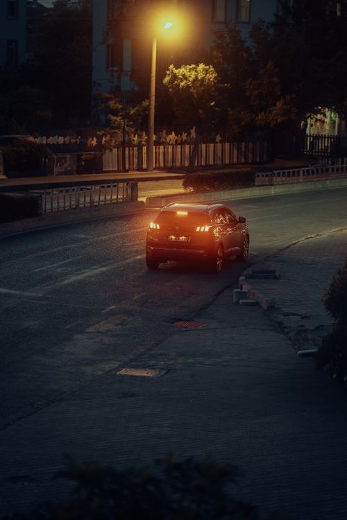 Free A car on a dimly lit city street with glowing taillights at night. Stock Photo