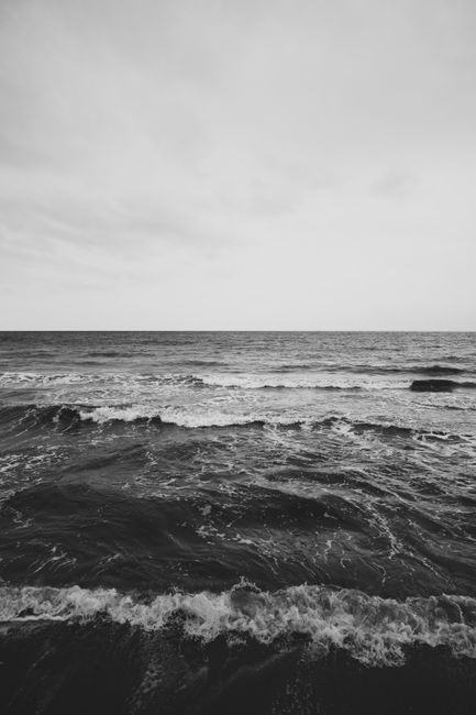 Monochrome photo of ocean waves and horizon, capturing the serene seascape in a vertical shot.
