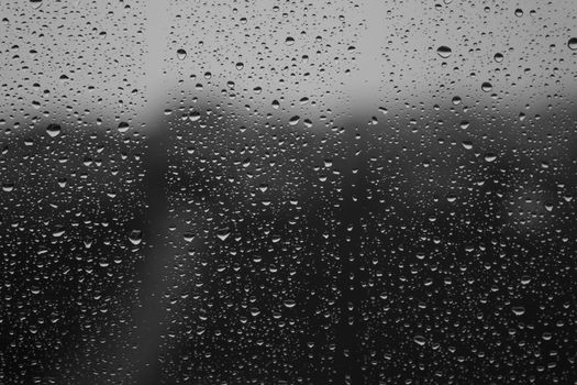 Captivating black and white close-up of raindrops on a window, creating a textured pattern.