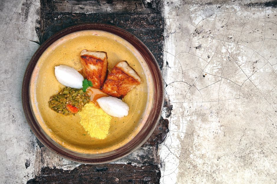Top view of a traditional fish dish with rice and vegetables on a rustic plate, perfect for food photography. - Traditional Bajan Food Guide (Local Dishes)