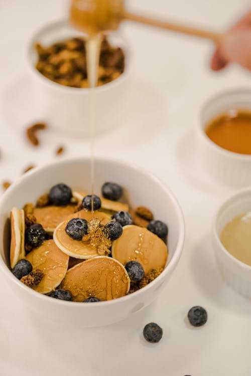 A bowl of pancakes with blueberries and honey