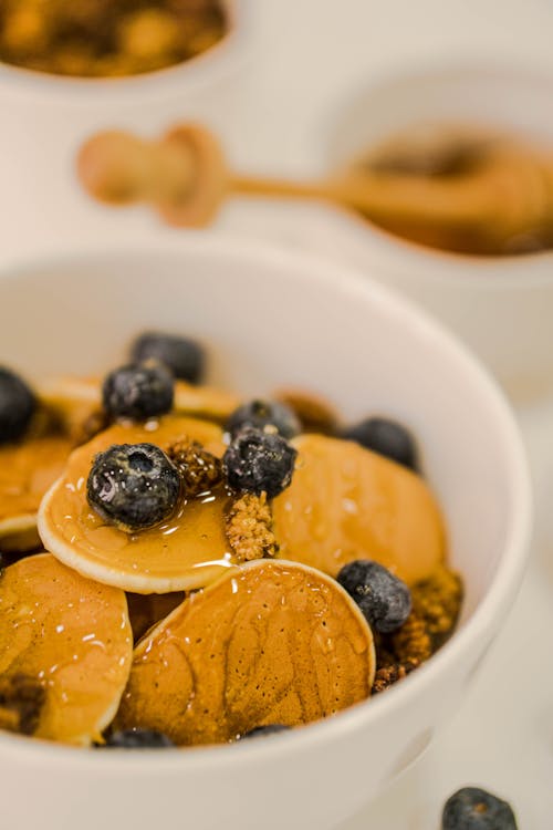 A bowl of pancakes with blueberries and honey