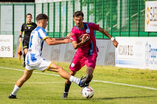 Two athletes playing soccer with intensity during a competitive match on a green field.