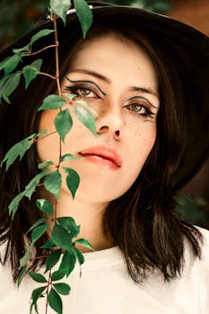 Artistic portrait of a young woman with freckles, wearing makeup and a sun hat.