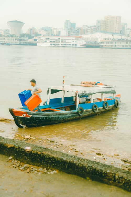 Free A fisherman unloads catch from a traditional boat in the bustling Saigon River, Ho Chi Minh City. Stock Photo