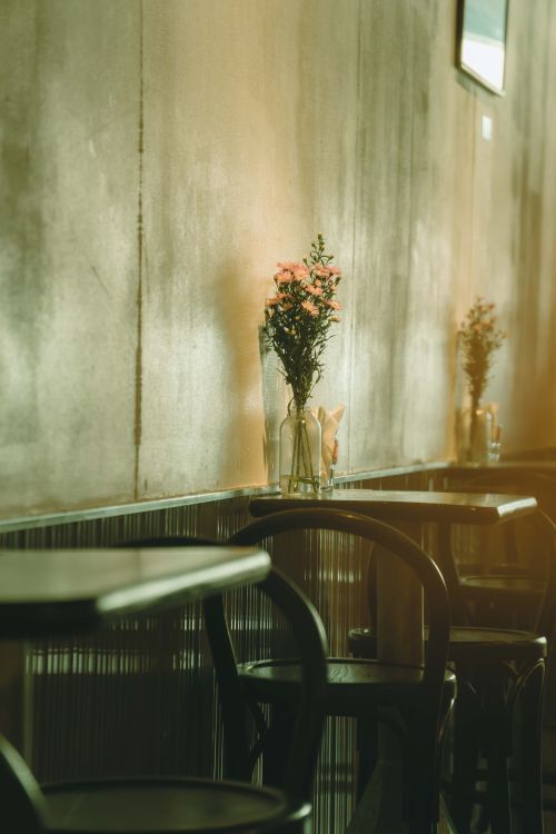 Free Serene café interior in Ho Chi Minh City with flowers on wooden tables. Stock Photo