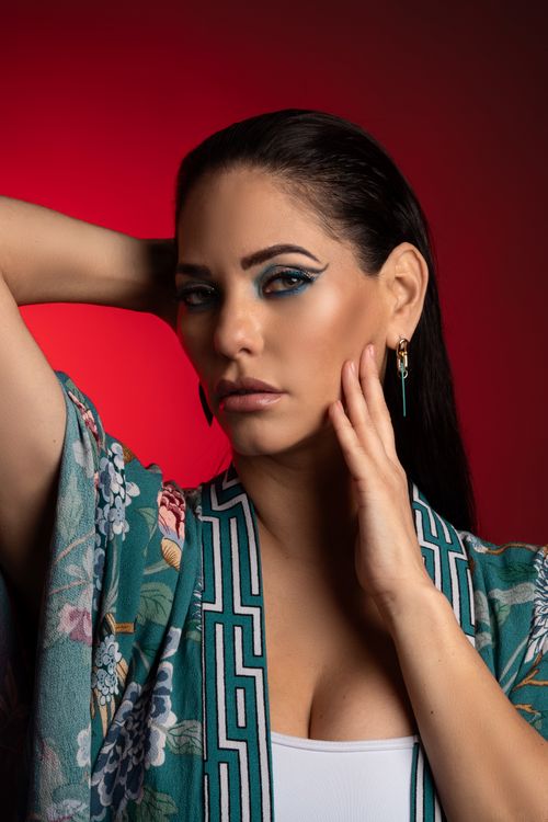 Free Studio shot of a woman in a floral kimono with bold makeup against a red background. Stock Photo