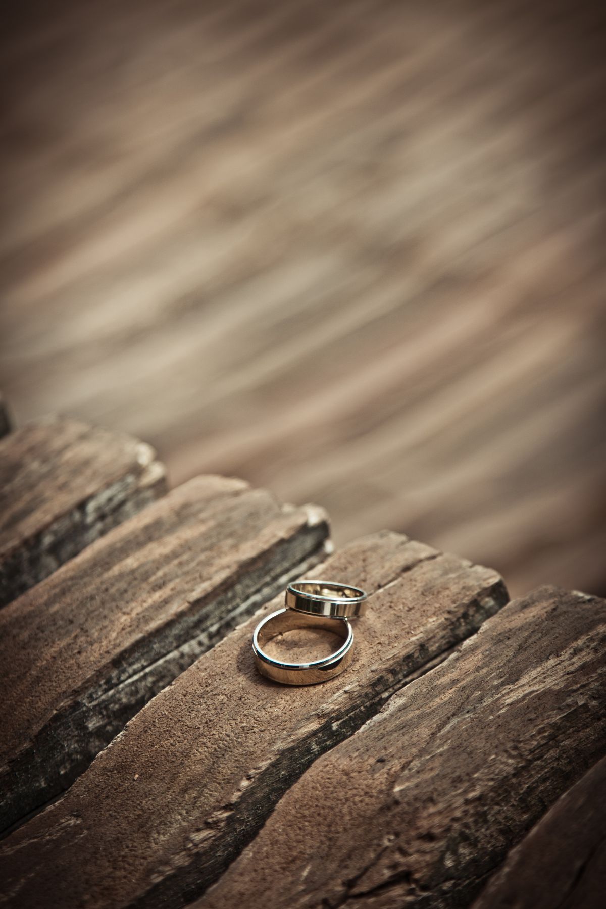 two plain silver-tone men's wedding bands on weathered wood — the white gold look without the white gold price