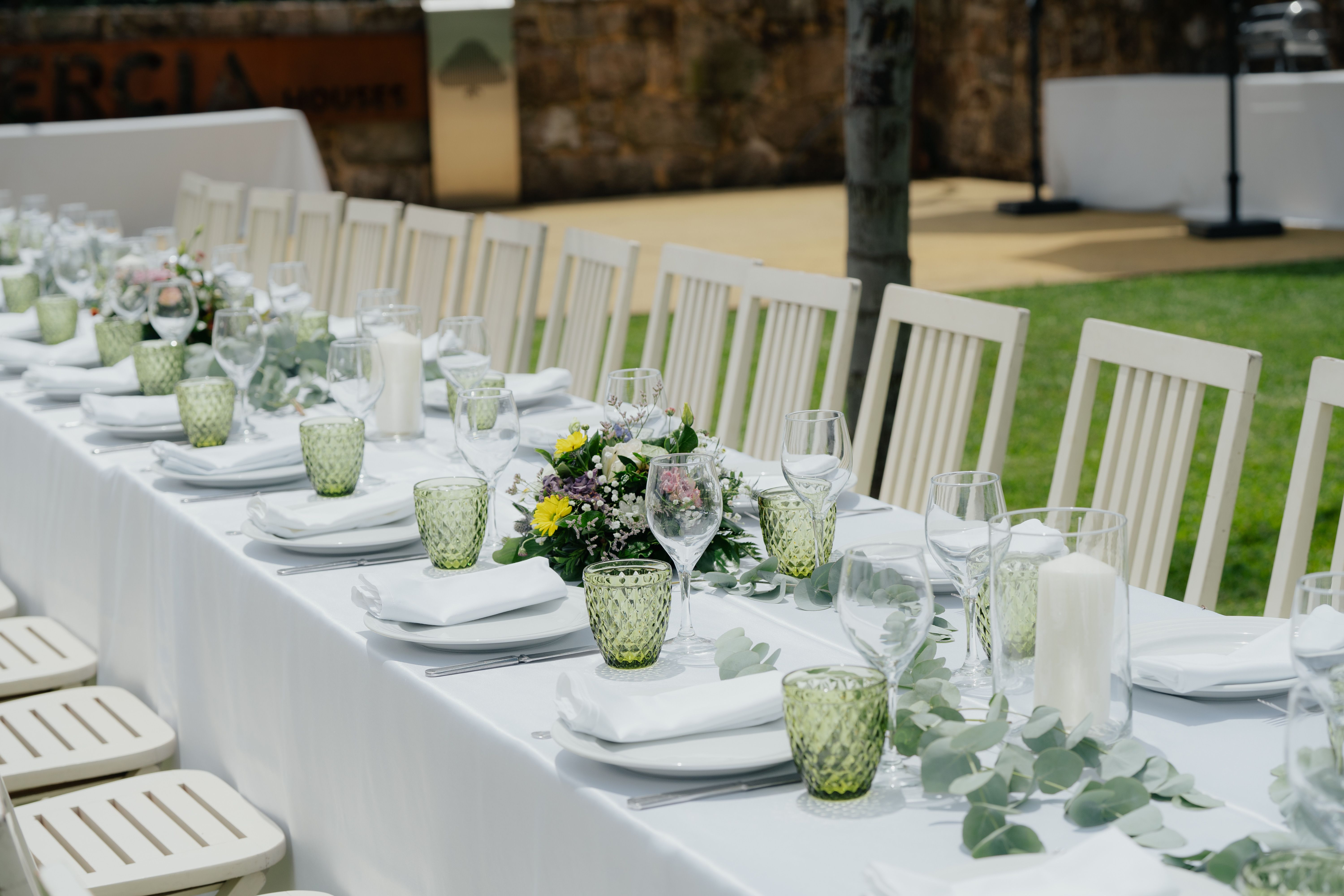 hacienda white summer party — An elegant outdoor table setup with chairs and floral centerpieces ideal for a garden event.