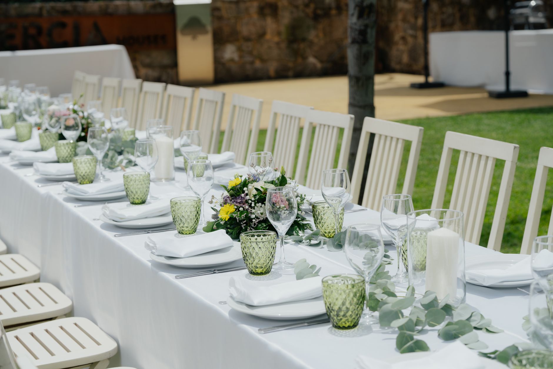 hacienda white summer party — An elegant outdoor table setup with chairs and floral centerpieces ideal for a garden event.