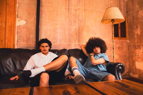 Free Stylish young men sitting comfortably on a leather couch in a rustic room setting. Stock Photo