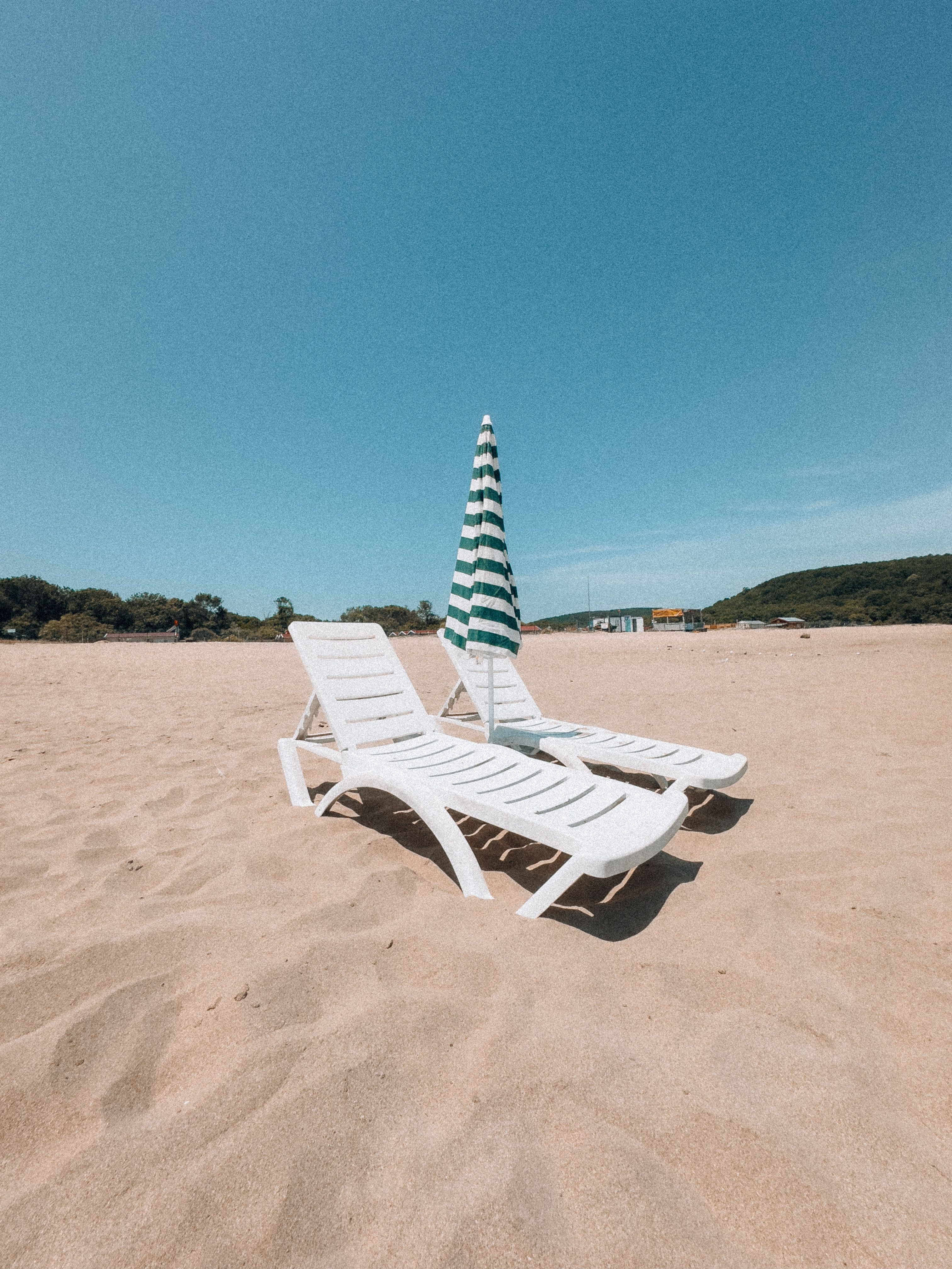 Beach chairs and umbrella arranged beside the coast