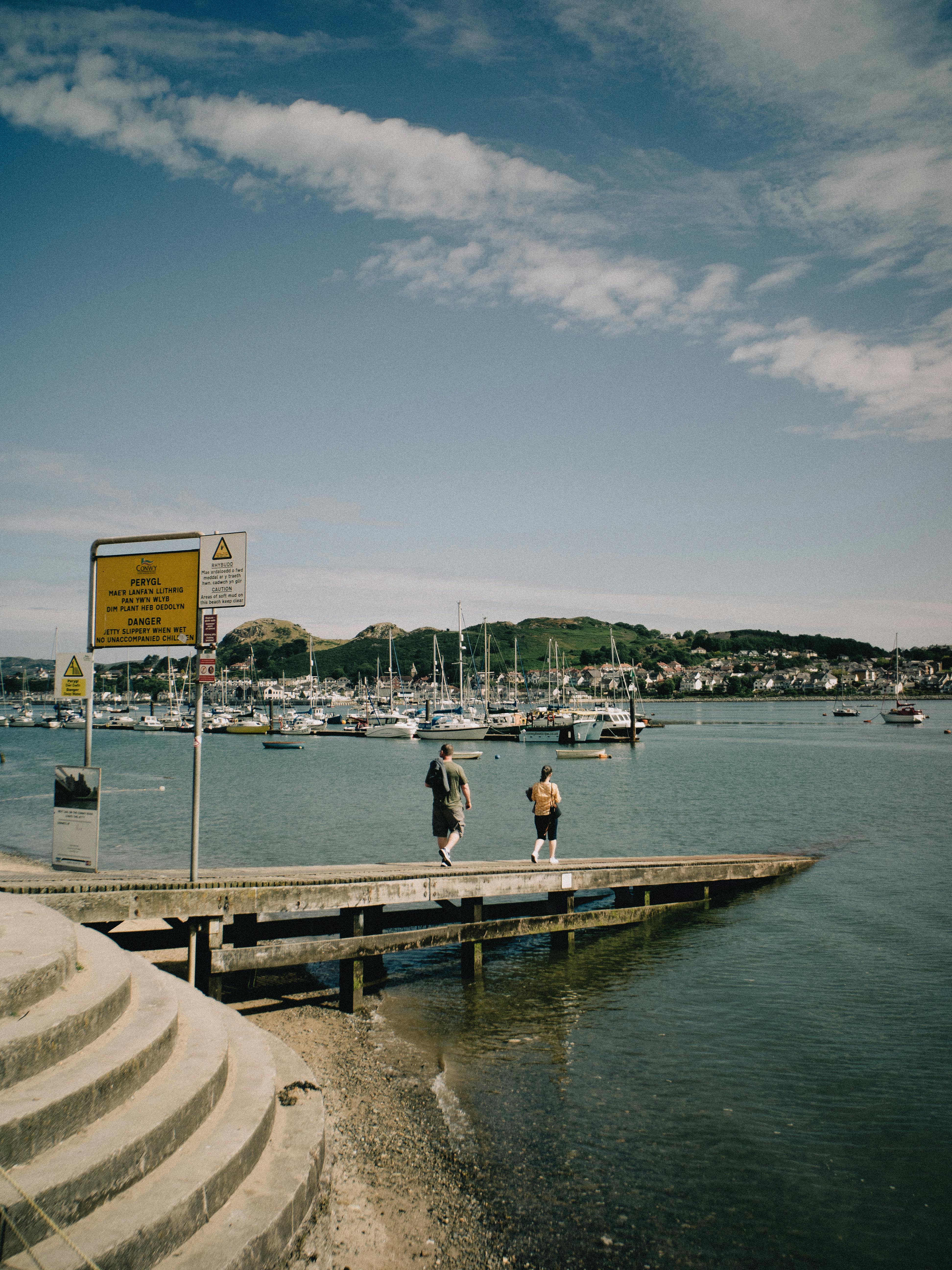 A picturesque scene of Conwy Harbor with boats and a distant town view under a clear sky.