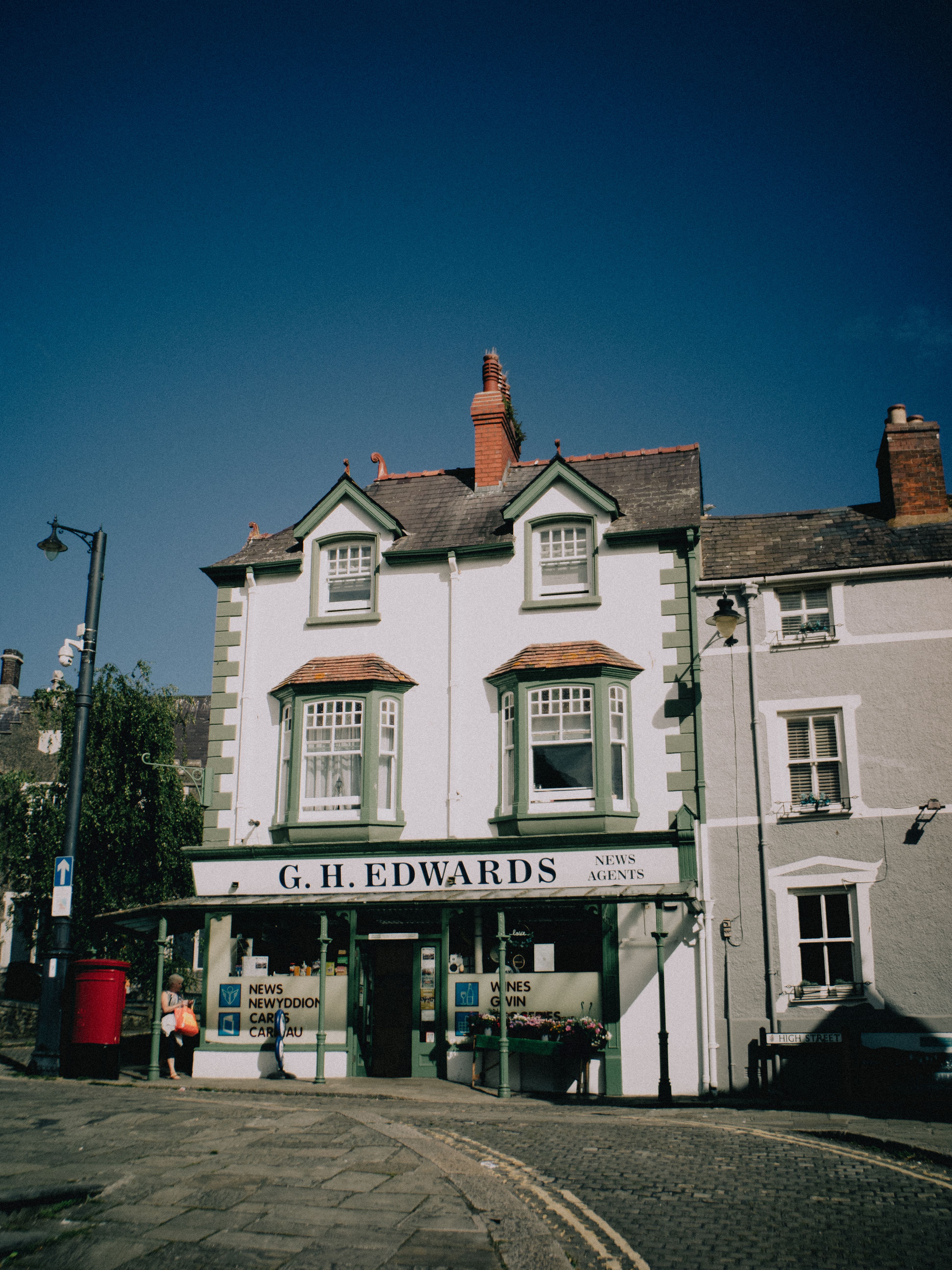Picturesque view of a historic street in Conwy, Wales featuring G.H. Edwards newsagents.