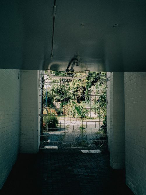 Free View through an archway into a lush garden in Conwy, Wales, showcasing intricate ironwork. Stock Photo