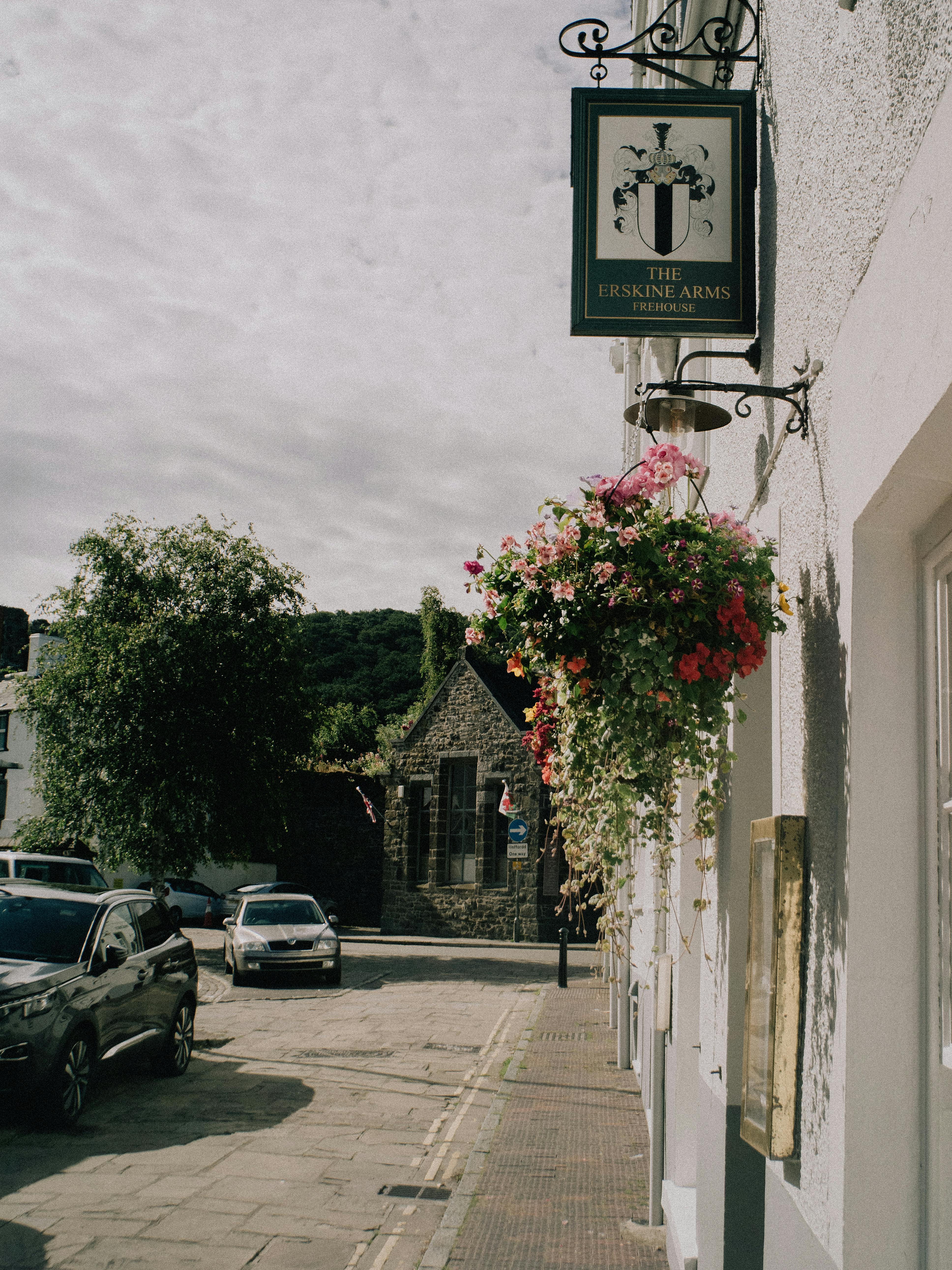 Charming street scene in Conwy, Wales featuring the Erskine Arms and vibrant flowers.