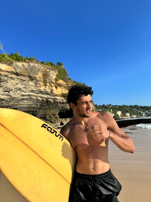 Free Shirtless man with surfboard enjoying a sunny day at the beach. Stock Photo