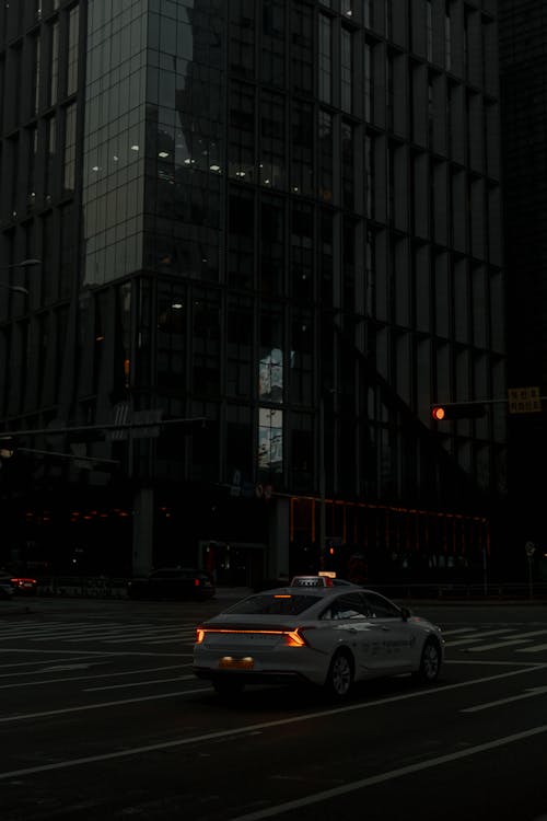 A car is driving down a street at night