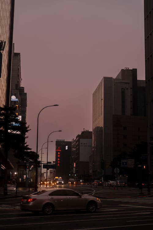 A city street with cars and buildings at dusk