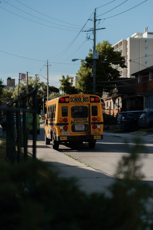 Free A yellow school bus drives down a quiet urban street lined with buildings. Stock Photo