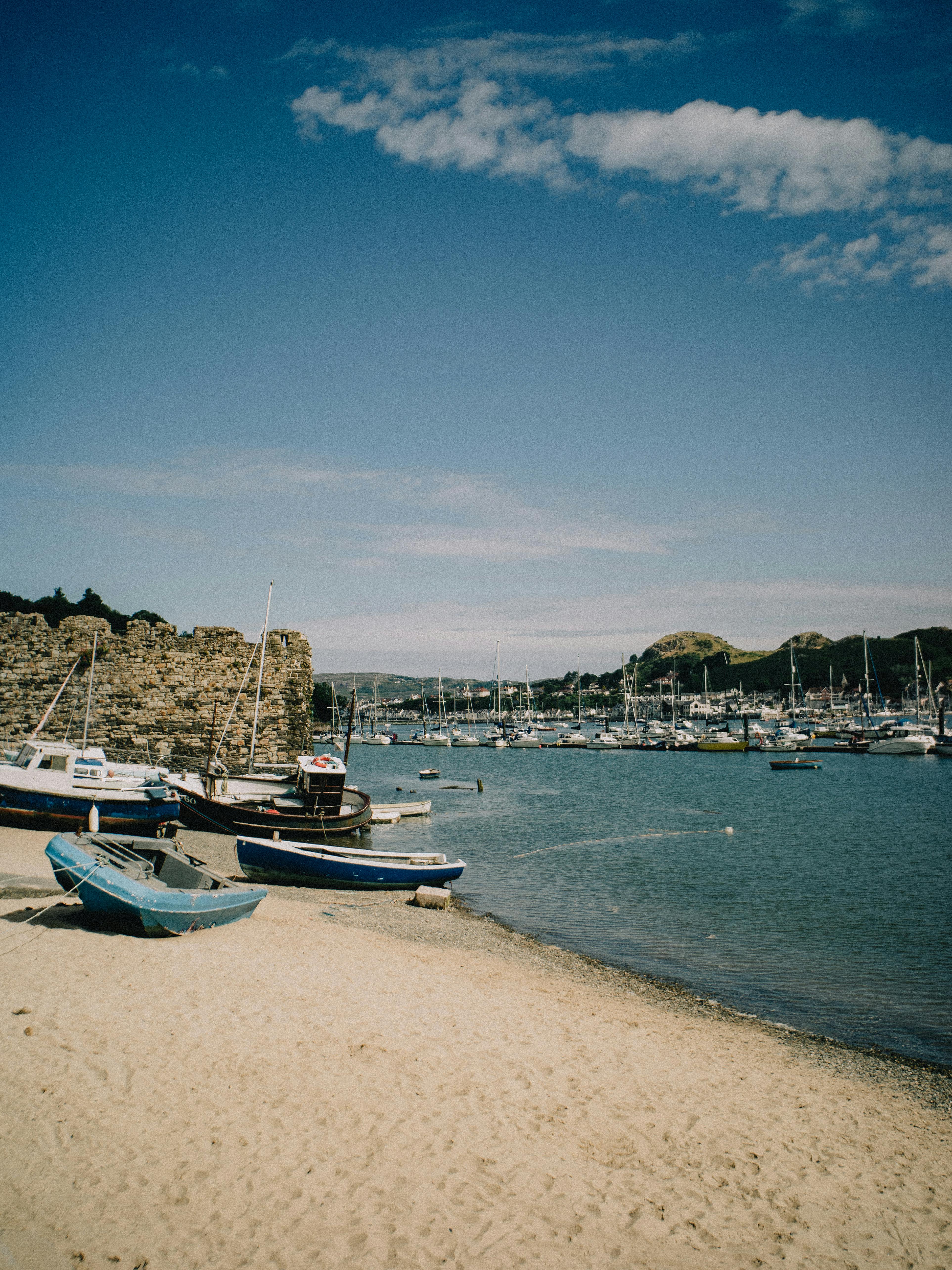 Idyllic coastal scene of Conwy harbor in Wales, featuring boats and sunny skies.
