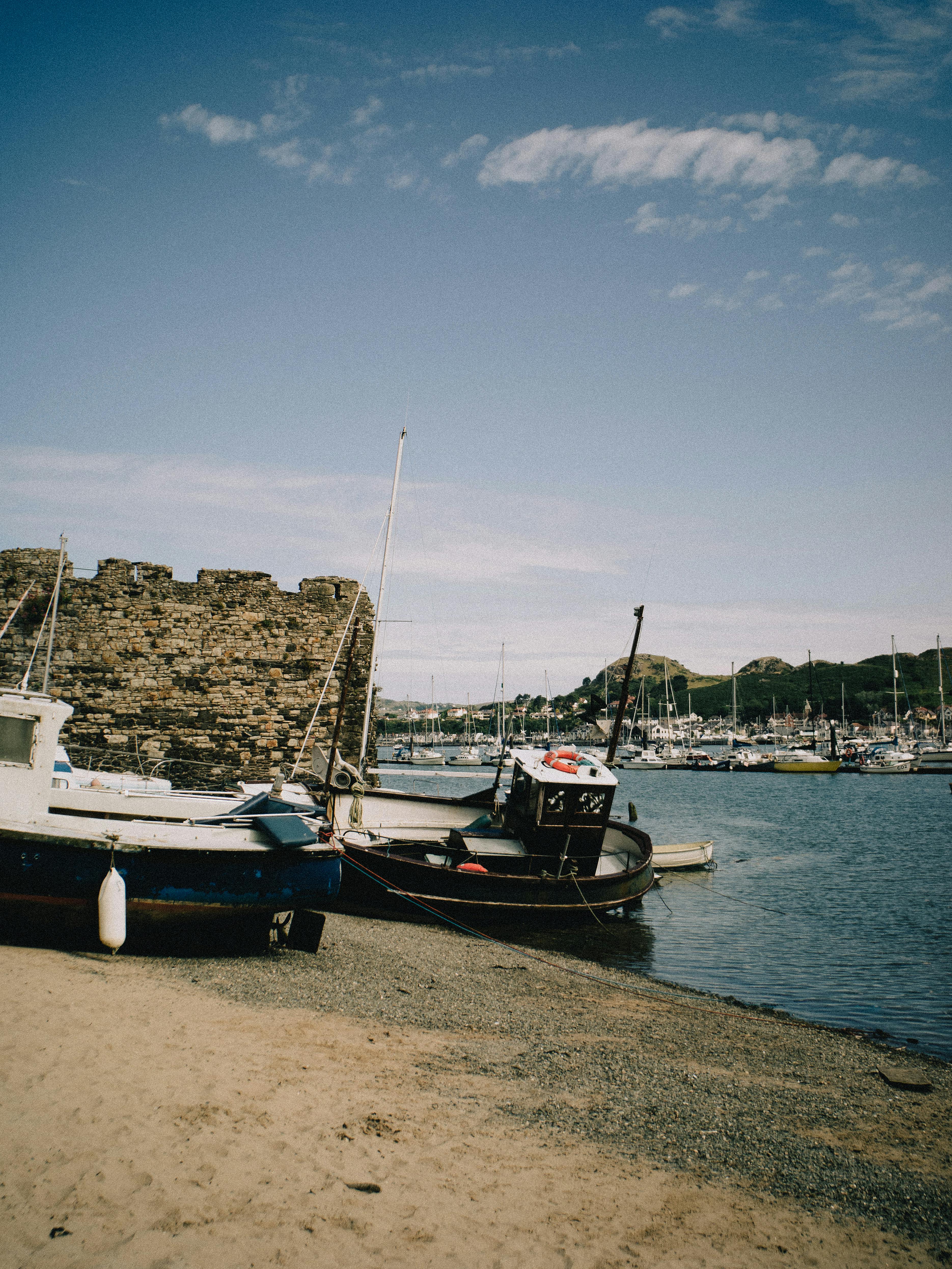 Idyllic view of boats by Conwy Castle walls in Wales, capturing rustic charm.