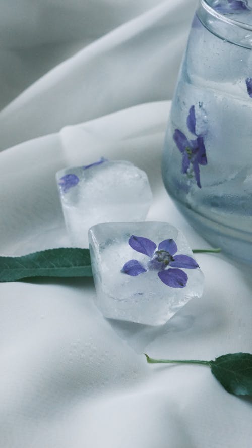 Ice cubes with flowers and leaves on a white cloth
