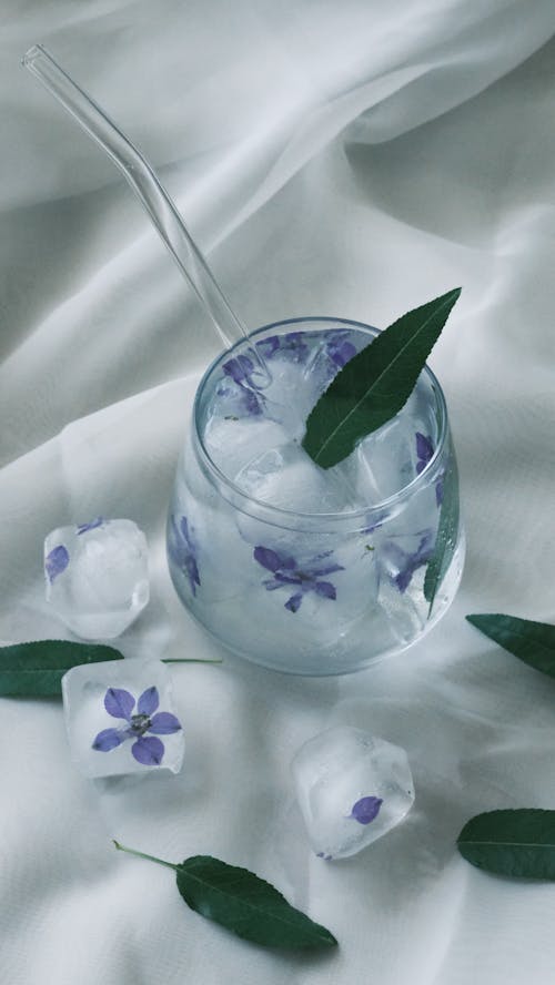 A glass of water with flowers and leaves on it