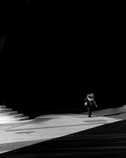 Free A lone figure walks in a dramatic black and white urban London setting, capturing light and shadow play. Stock Photo