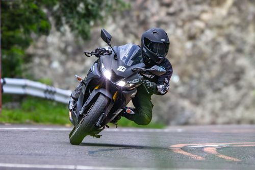 Free Dynamic action shot of a motorcycle rider leaning into a curve on a scenic road. Stock Photo