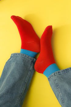Artistic close-up of red socks paired with jeans on a vibrant yellow background.