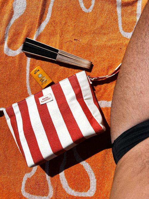 Free A vibrant beach setup with summer essentials: striped pouch, sun lotion, hand fan. Stock Photo