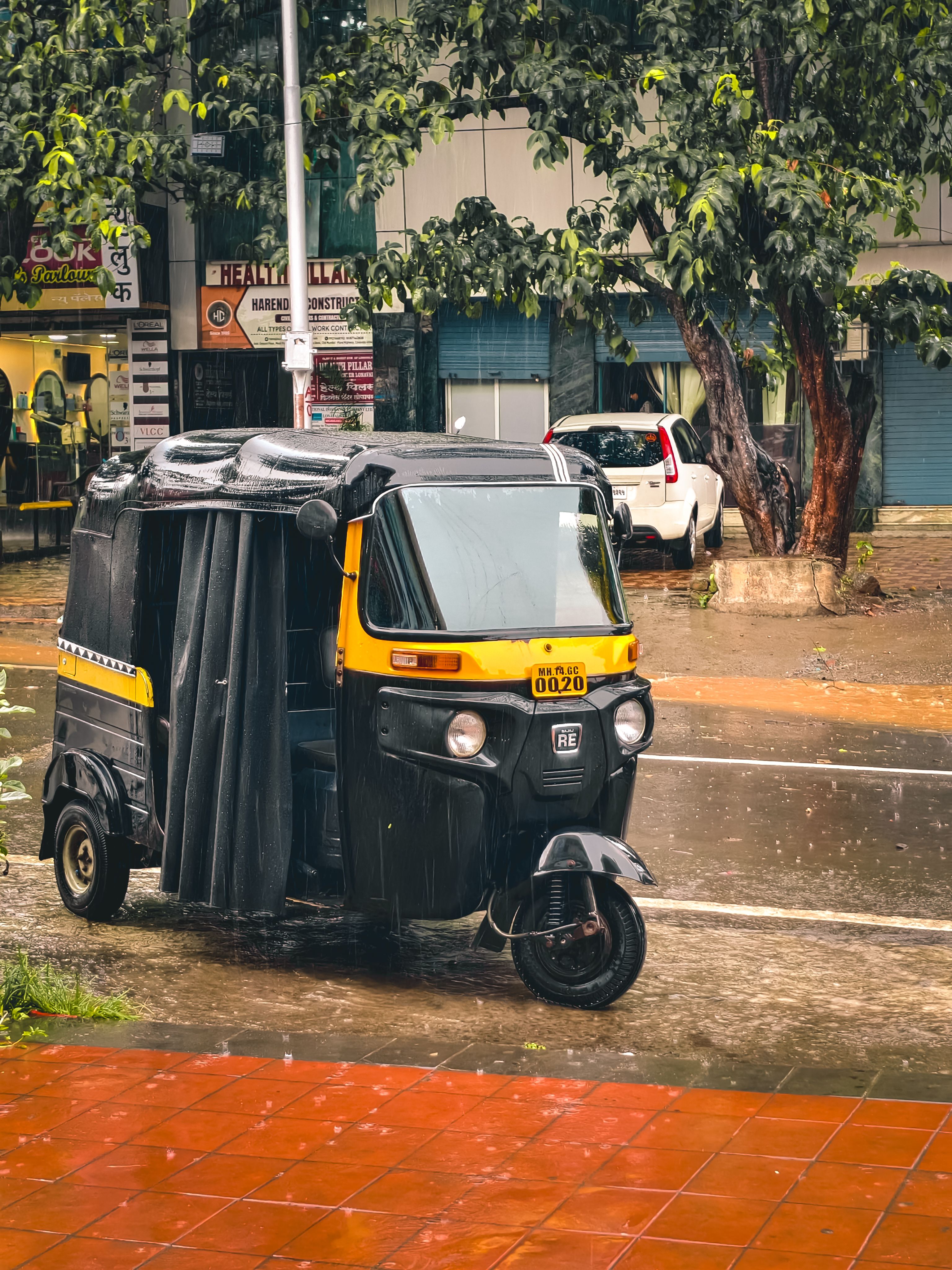 Auto rickshaw parked on a rainy city street, capturing urban transportation and weather.