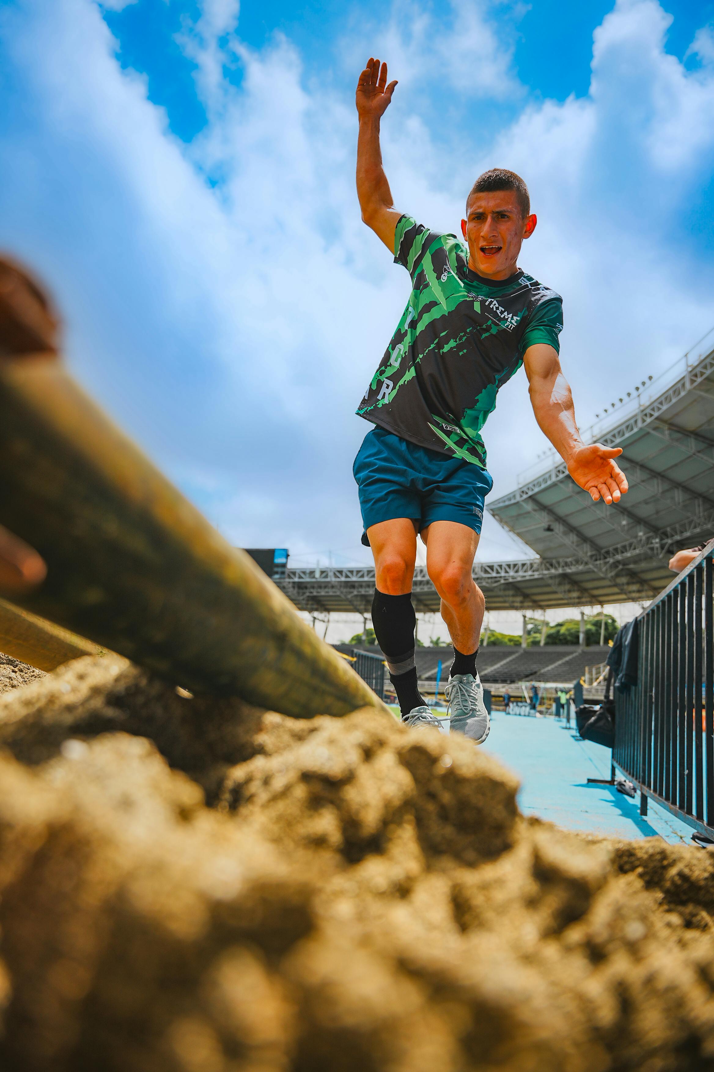 Dynamic shot of an athlete balancing during an obstacle course event in a stadium.