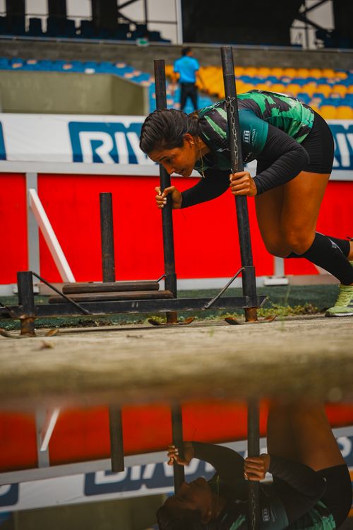 Free Focused woman athlete pushing a sled on a wet sports field, showing strength and determination. Stock Photo