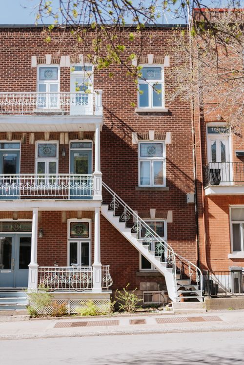 Free Charming urban townhouse featuring a classic wrought iron staircase and brick exterior. Stock Photo