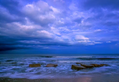 A beach with rocks and clouds in the sky