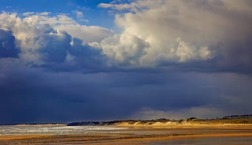 A beach with clouds and sand under a cloudy sky