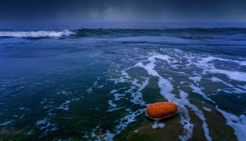 An orange ball sits on the beach at night