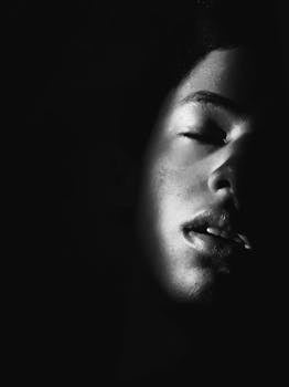 一张高对比度的黑白特写肖像中，一名女性的脸部隐没在阴影里