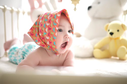 無料 ベッドでヘッドスカーフを身に着けている幼児 写真素材