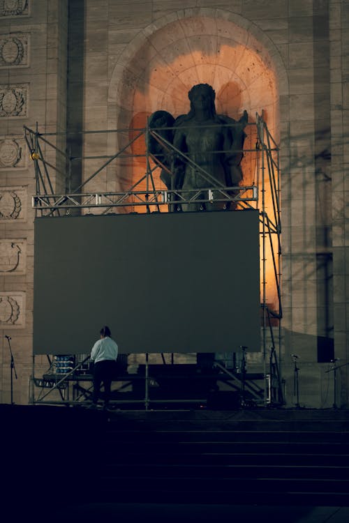 A man is standing on a stage with a large screen