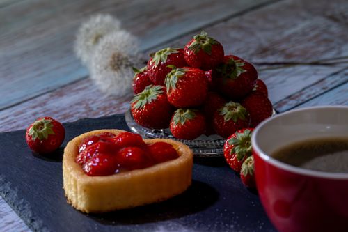 Free Delicious heart-shaped strawberry tart paired with fresh coffee and strawberries. Stock Photo