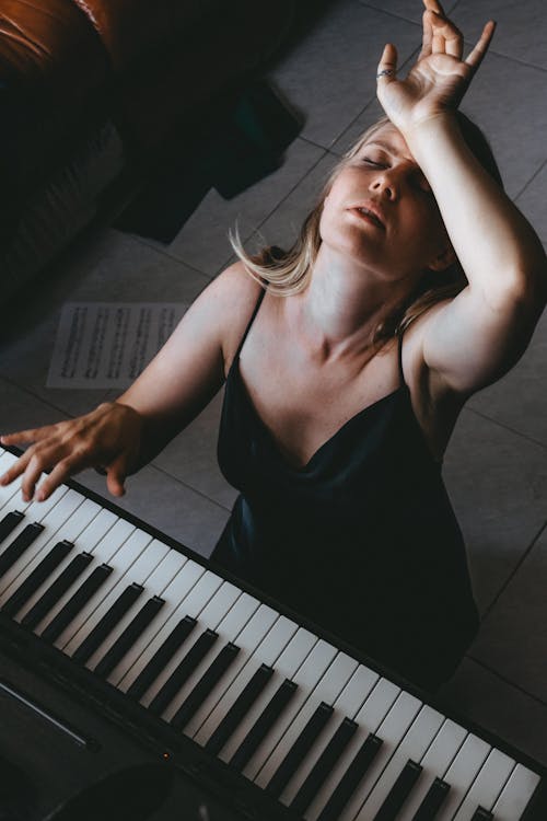 Free A woman playing the piano in front of a window Stock Photo