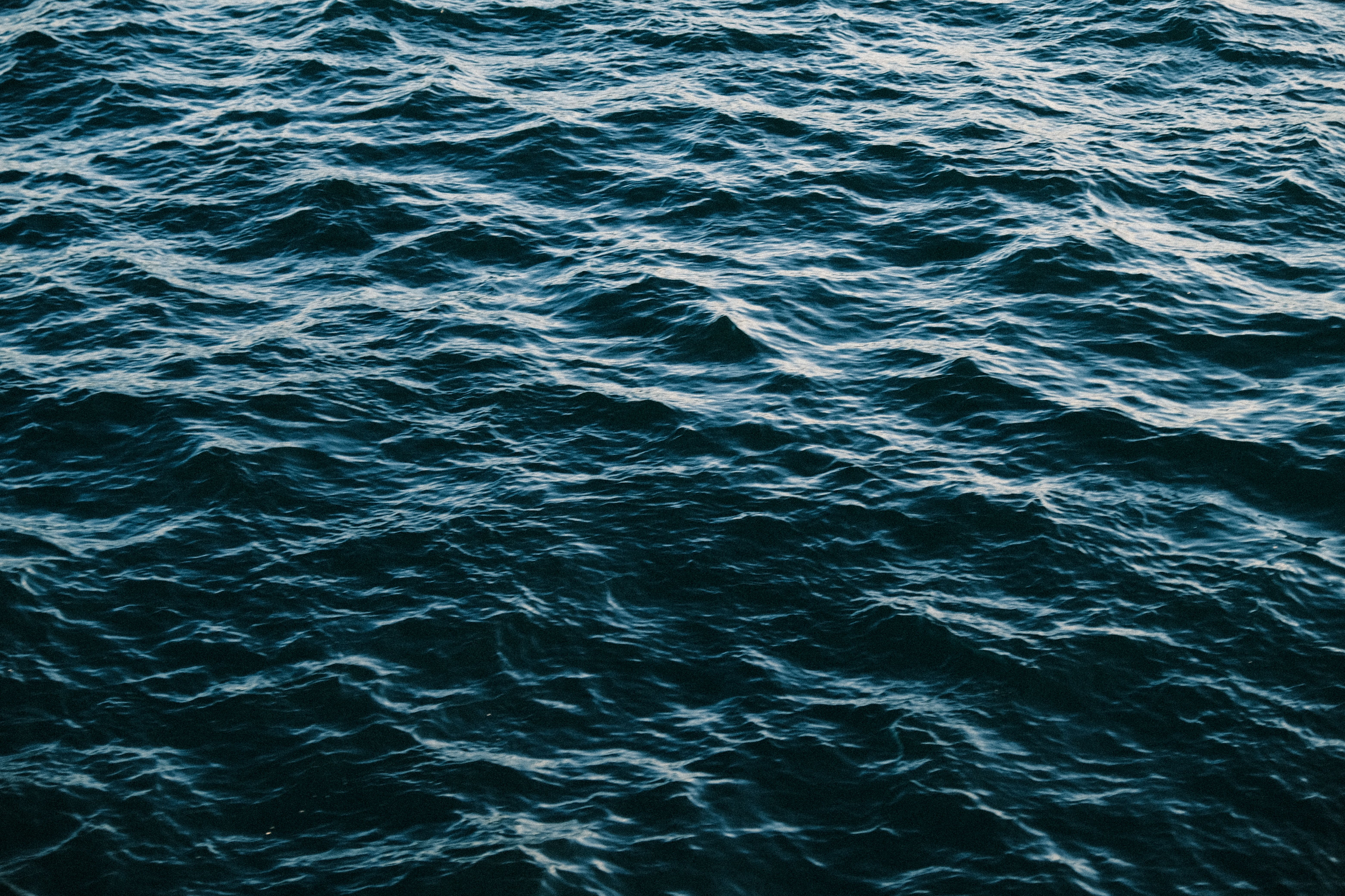 Dynamic close-up shot of choppy ocean waves under daylight, showcasing natural wavy patterns and deep blue hues.