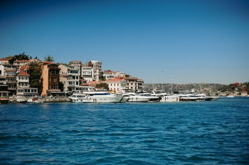 Free Beautiful waterfront view of moored yachts against an urban backdrop under a clear blue sky. Stock Photo