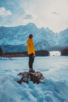 冬日明媚，一位身着黄色夹克的人正欣赏着白雪皑皑的优美山景